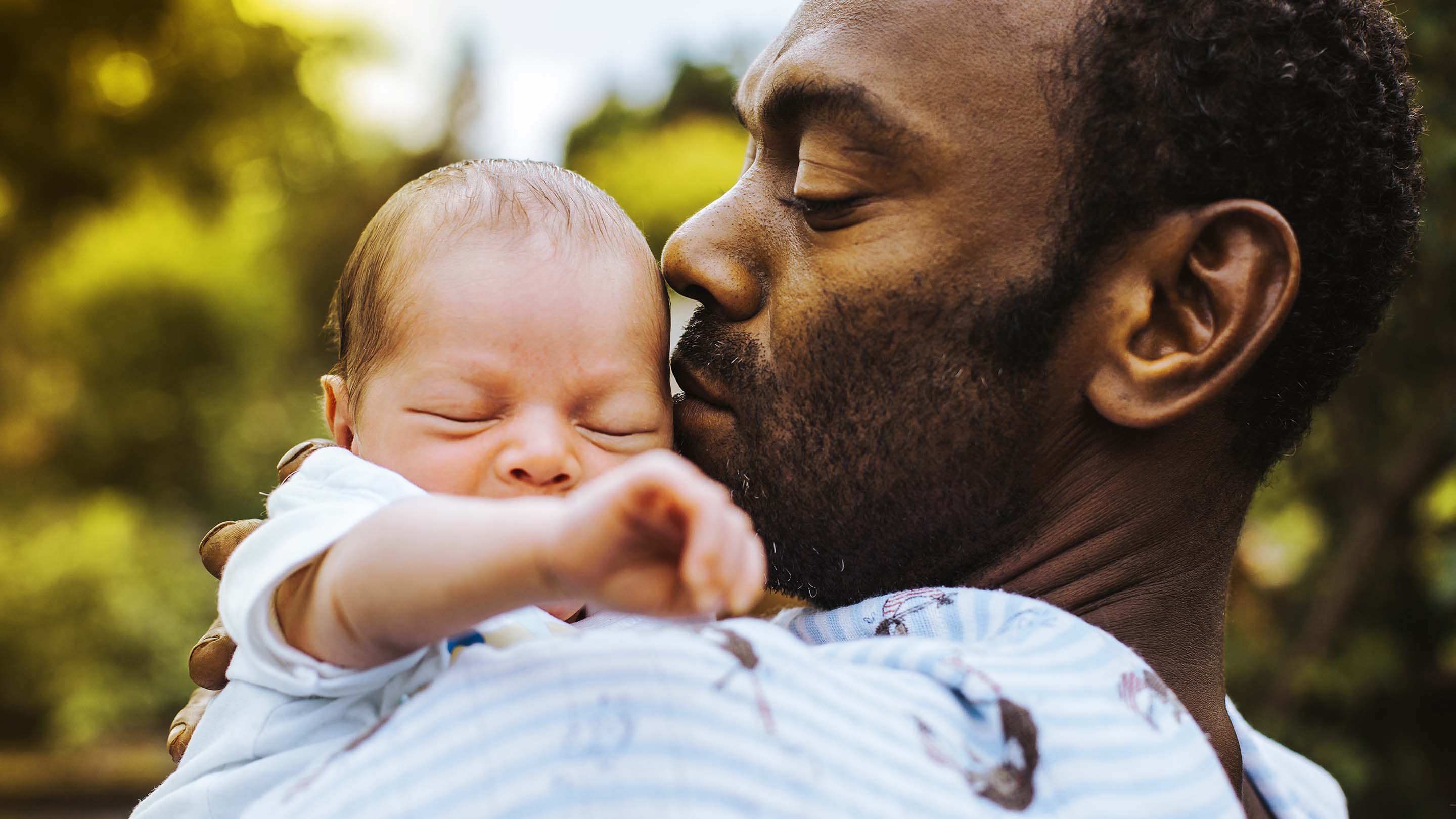 Man holding new born baby on his shoulder